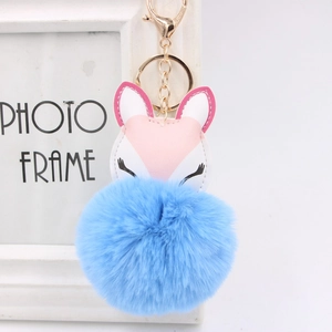 Detail of fox plush keychain featuring pink leather ears and a large light blue faux fur ball