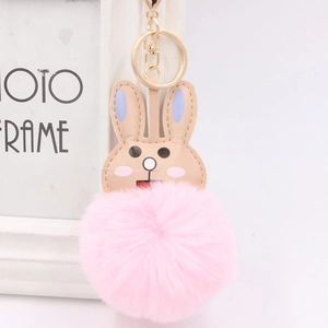 Close-up of cute pink faux fur bunny keychain with golden clip near photo frame