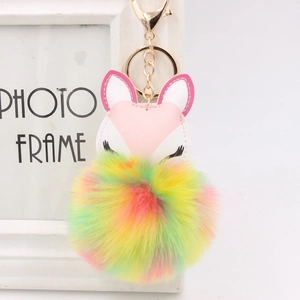 Detail of fox plush keychain featuring embroidered eyes and a colorful rainbow fur ball