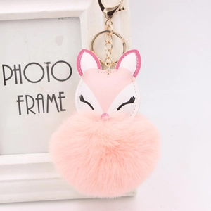 Detailed close-up of pink fox pom-pom keychain with gold hardware and embroidery