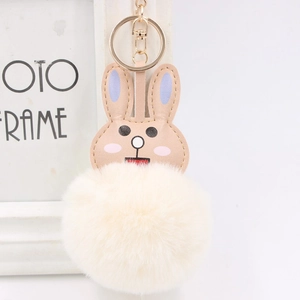 Detail of cute rabbit fur ball keychain with khaki leather ears and soft white pompom