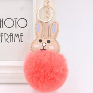 Detail of cute coral red faux fur pompom keychain with brown leather rabbit head design