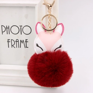 Detail of fox plush keychain with pink faux leather embroidery and dark red fluffy ball