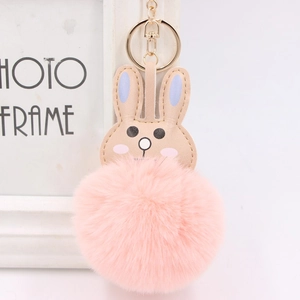 Detail of cute pink faux fur bunny keychain with golden metal ring and soft leather ears