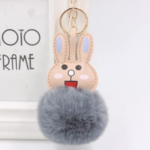 Close-up of cute faux fur pompom rabbit keychain with golden metal ring and hook