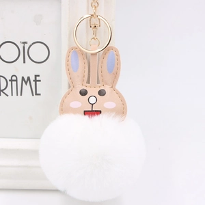 Macro shot of fluffy rabbit keychain with white faux fur pompom and golden lobster clasp