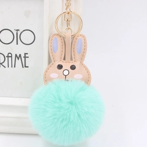 Close-up of a mint green plush pom pom keychain with a cute pink leather bunny head