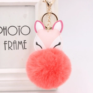 Detail view of a coral pink faux fur fox keychain with golden hardware for bags