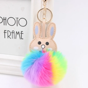 Detail of colorful rainbow faux fur pompom keychain with rabbit ears and golden clasp