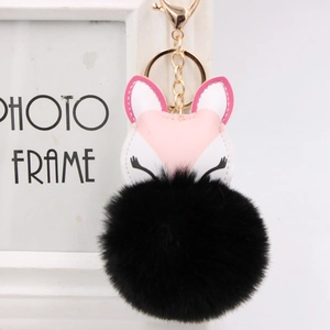 Detail of pink and white fox pendant with large black fluffy fur pom pom on gold lobster clasp