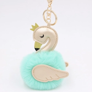 Detailed close-up of mint green swan plush charm with golden wings and a crown decoration