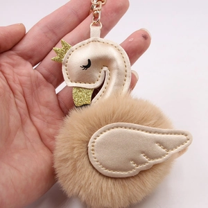 Elegant swan keychain featuring champagne gold faux leather and a fluffy brown plush pompom