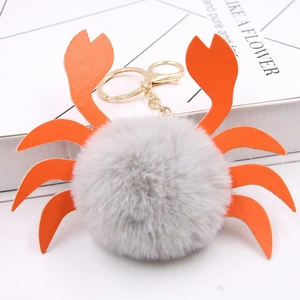 Détail du porte-clés crabe en peluche grise avec pinces en cuir orange et boucle dorée