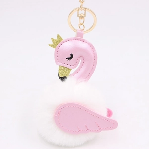 Close-up of a pink swan keychain with white plush pom-pom and golden crown details