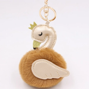 Detail of swan plush keychain with brown fur, PU leather neck and golden crown clip