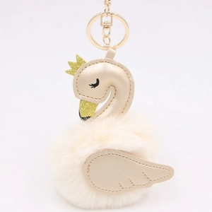 Detail of swan bag charm with champagne PU leather, gold crown and soft plush pom pom