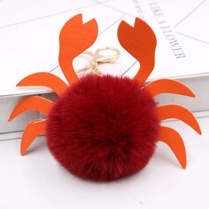 Détail d'un bijou de sac crabe en peluche avec pinces en cuir orange et anneau doré