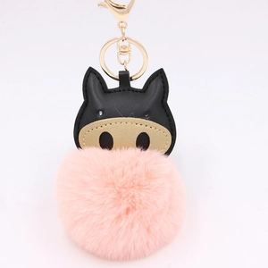 Detail of pink plush pompom keychain with golden lobster clasp and black leather trim