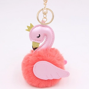 Detail of pink swan plush keychain with gold crown and orange faux fur pompom ball