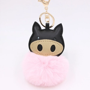 Detail of cartoon pig plush keychain with pink fur ball and golden metal ring