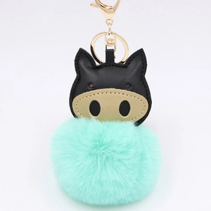 Close-up of mint green plush pig keychain with black leather ears and gold metal clasp