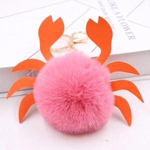Détail d'un porte-clés crabe en peluche rose avec pinces orange et fermoir doré en métal