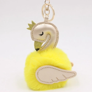 Detailed shot of yellow plush swan keychain with champagne gold leather wings and crown