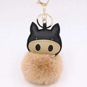 Detailed view of plush pompom keychain with creative pig face and gold hardware