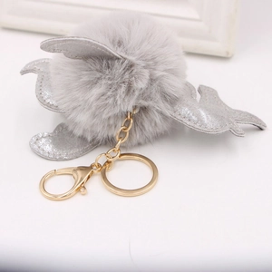 Détail d'un porte-clés en peluche grise avec des ailes pailletées et un fermoir doré