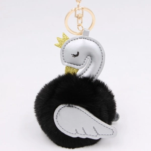 Detail of swan faux fur pompom keychain with silver leather wings and golden crown