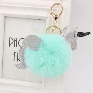 Détail d'un porte-clés licorne en peluche vert menthe avec ailes argentées et fermoir doré