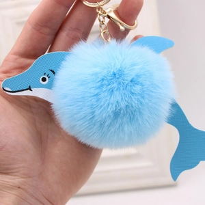 Close-up of light blue plush dolphin keychain with gold metal clasp and leather texture