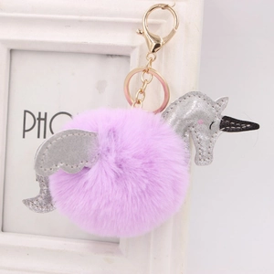Détail d'un porte-clés licorne à pompon violet avec ailes en paillettes et fermoir doré