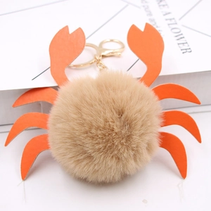 Détail d'un porte-clés crabe en peluche avec boule kaki et pinces en simili cuir orange