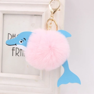 Cute dolphin plush keychain with pink pom-pom and blue accents on a golden metal hook