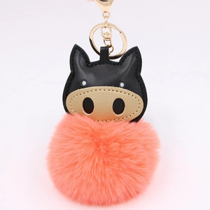 Detailed close-up of cartoon pig keychain featuring golden nose and pink plush pompom
