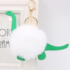 Close-up of fluffy white fur ball dinosaur keychain with green leather and gold hardware