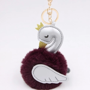 Close-up of swan plush keychain with purple faux fur ball and golden crown detail