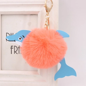 Detail of blue leather dolphin head and coral plush ball on a golden metal keychain