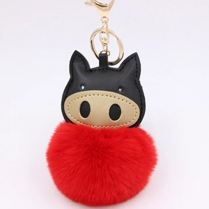 Detail of creative pig keychain featuring a large red plush pom-pom and black leather head