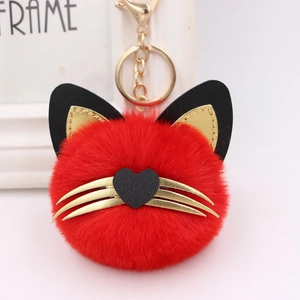 Detail of red plush cat head keychain with gold whiskers and heart nose accessory