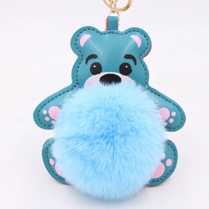 Détail d'un porte-clés ours en similicuir bleu avec pompon et anneau doré