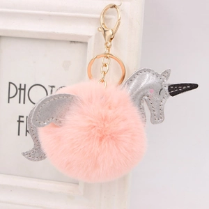 Détail d'un porte-clés licorne en pompon rose avec paillettes argentées et crochet doré