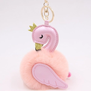 Detail of pink swan plush keychain with faux leather wings and golden crown decoration
