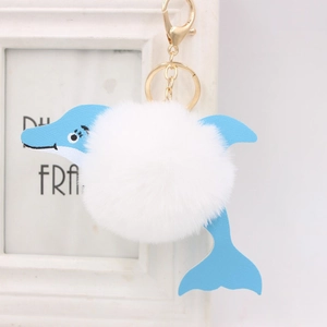 Cute white plush dolphin pom pom keychain with blue leather fins and gold hardware