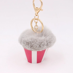 Close-up of grey plush pompom cake keychain with red striped cup and gold hardware