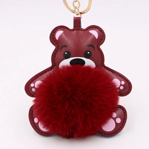 Détail du porte-clés ours en peluche bordeaux avec pompon et mousqueton doré chic