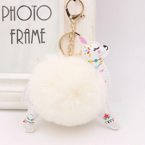 Close-up of white plush pompom and printed alpaca pendant with golden metal clasp