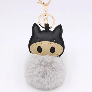 Detailed view of plush pig keychain with black leather face and gold metal clasp