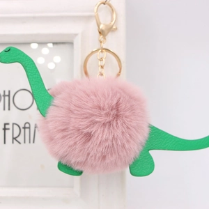 Detail of pink faux fur dinosaur keychain with green leather accents and gold lobster clasp